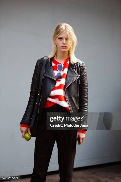 Model Line Kjaergaard holds and apple and wears a red leather jacket, Diane Von Furstenberg red striped sweater, and black pants during London...