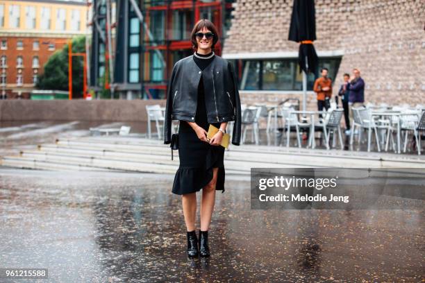 Model Sam Rollinson attends a show and wears black sunglasses, a leather jacket on her shoulders, dress, and booties during London Fashion Week...