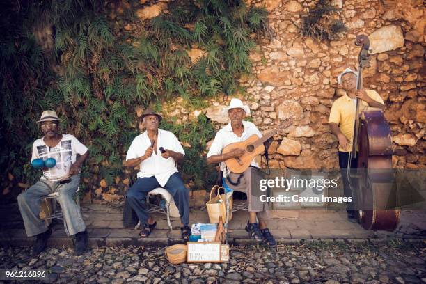 street musicians playing musical instruments against stone wall - maracas stock pictures, royalty-free photos & images