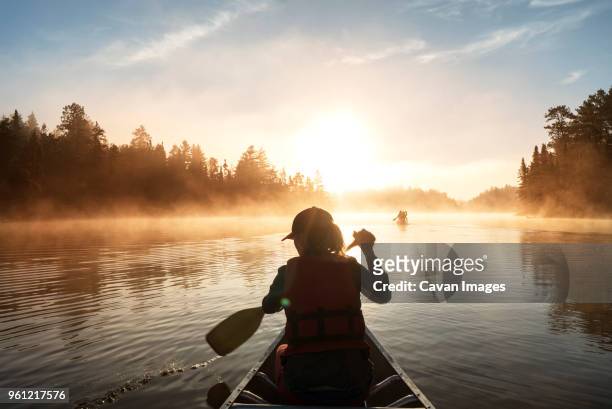 rear view of woman traveling in boat on lake - silhouette woman sunset stock pictures, royalty-free photos & images
