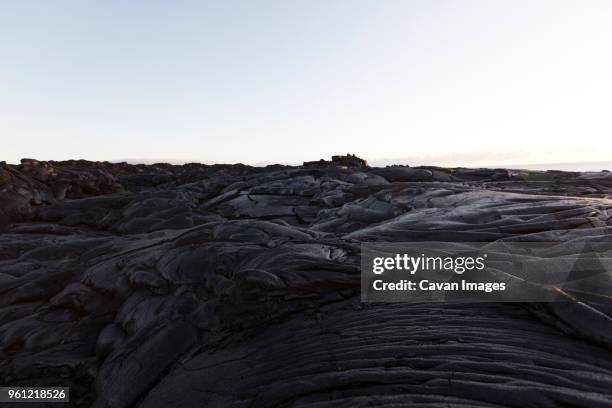 volcanic rocks at beach against clear sky - vulkanisch gesteente stockfoto's en -beelden