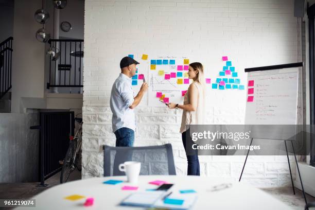 business people discussing while standing by adhesive notes at creative office - easel stand stock pictures, royalty-free photos & images