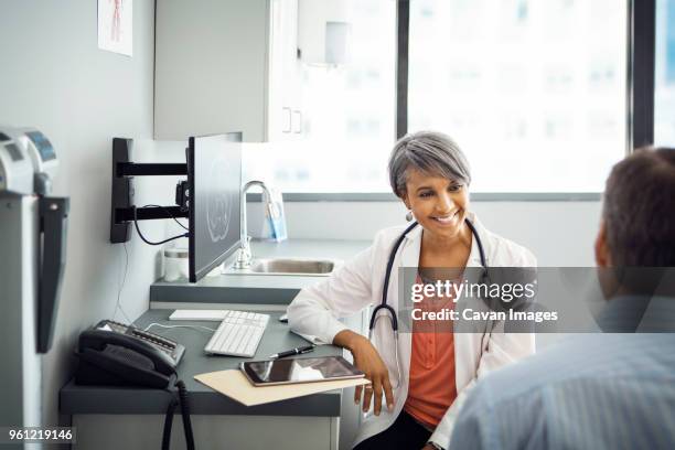 happy female doctor talking to male patient in clinic - male doctor man patient stock-fotos und bilder