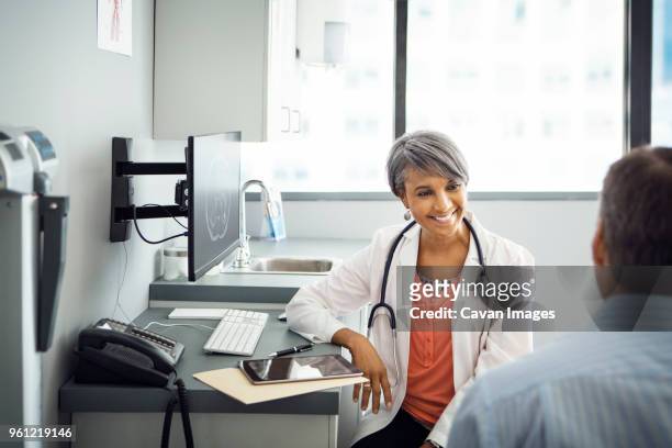 happy female doctor talking to male patient in clinic - adult patient with doctor and stethoscope photos et images de collection