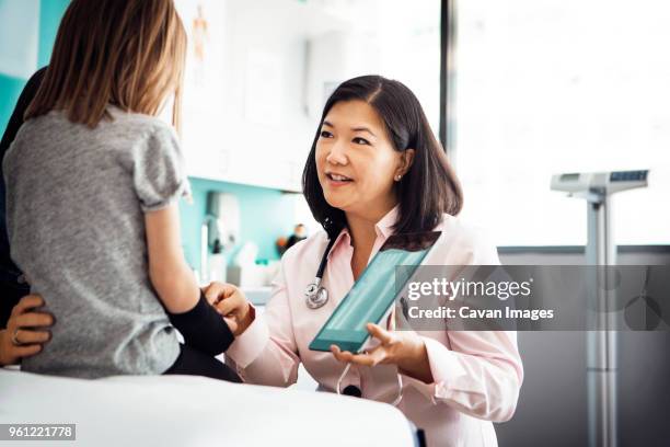 female doctor showing hand x-ray on tablet computer to girl in clinic - medical x ray fotografías e imágenes de stock