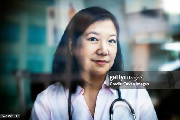 portrait of confident female doctor seen through window - doctor portrait stock pictures, royalty-free photos & images