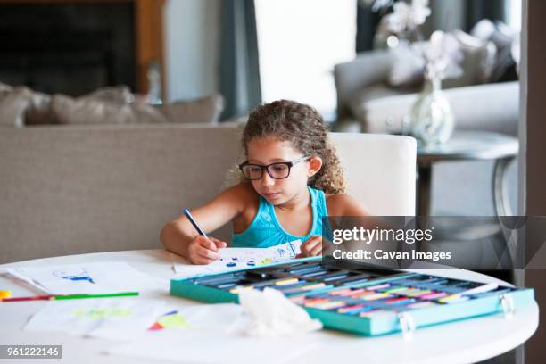 girl coloring with felt tip pen on paper at table - felt tip pen stock-fotos und bilder