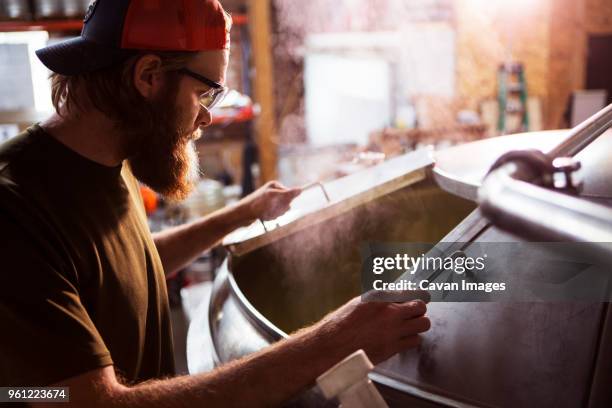 brewer looking in machinery at brewery - brewers stock pictures, royalty-free photos & images