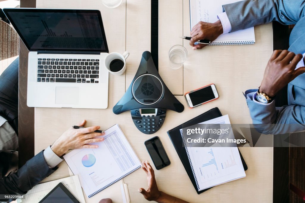 High angle view of business people analyzing reports in board room