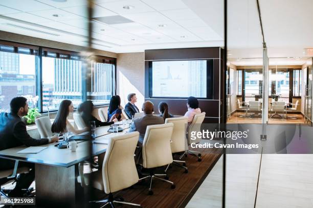 business people discussing in meeting at conference room seen through doorway - meeting room screen stock-fotos und bilder