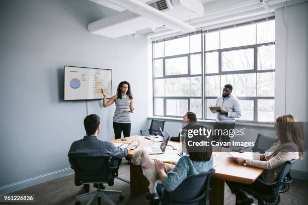 businesswoman explaining data to colleagues in meeting at board room - テレビ　会議 ストックフォトと画像