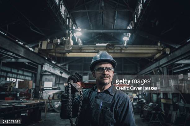 male worker carrying work tool looking away while standing in factory - steel worker stock pictures, royalty-free photos & images