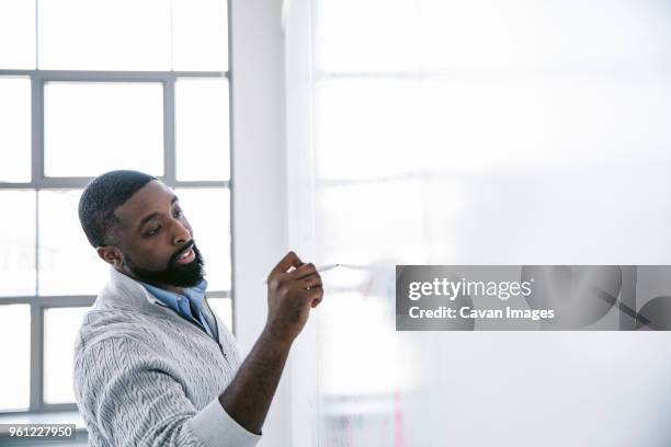 confident businessman writing on whiteboard with felt tip pen in office - felt tip pen stock-fotos und bilder