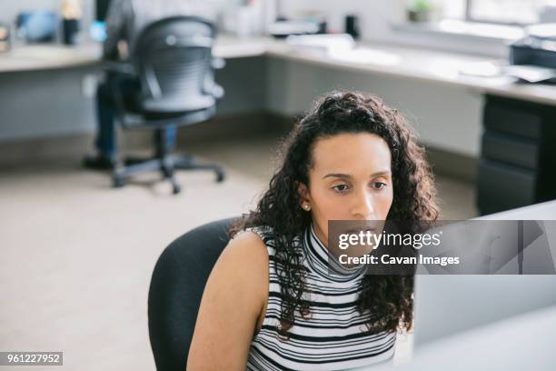 businesswoman using computer while male colleague in background - lower employee engagement stock pictures, royalty-free photos & images