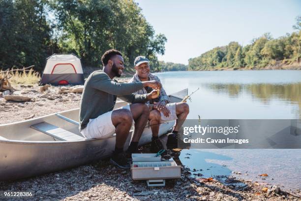 happy male friends adjusting fishing tackle on boat at lakeshore - missouri lake stock pictures, royalty-free photos & images