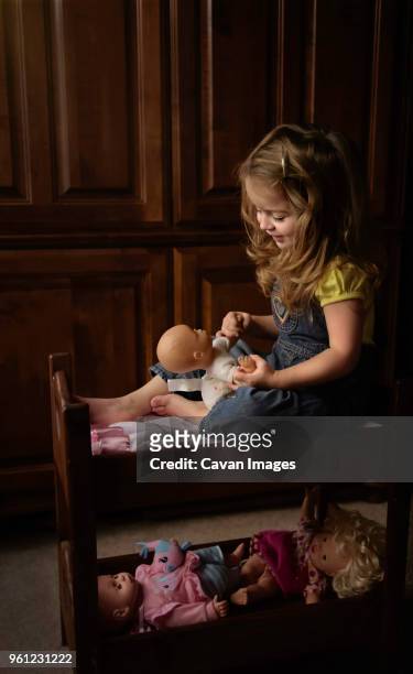 full length of girl playing with doll at home - doll house stockfoto's en -beelden
