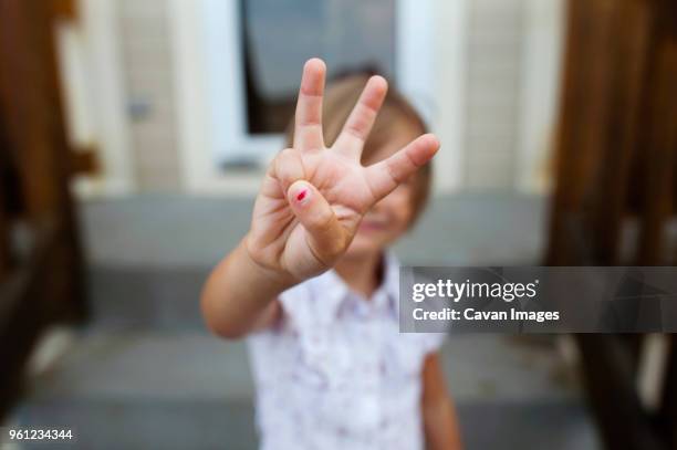 girl showing three fingers while standing on steps - two hands stock-fotos und bilder