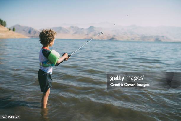 side view of boy fishing while standing in river during sunny day - kernville stock pictures, royalty-free photos & images