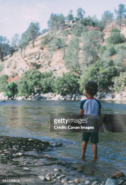 rear view of boy fishing while standing in lake against mountains - kernville stock pictures, royalty-free photos & images