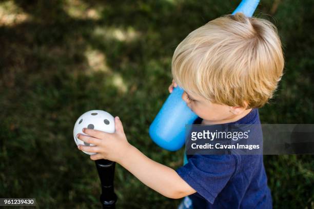 high angle view of boy playing t-ball in backyard - backyard baseball stock-fotos und bilder