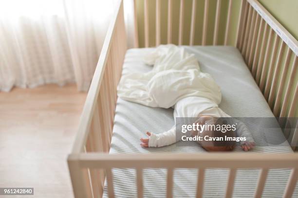 high angle view of baby boy sleeping in crib at home - wieg stockfoto's en -beelden