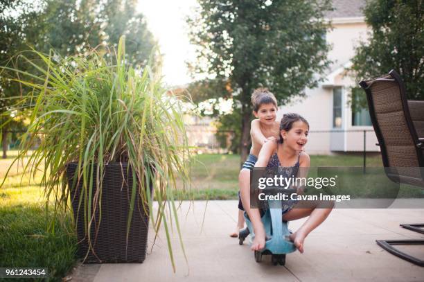 playful siblings playing on moped scooter at backyard - mod scooter stock pictures, royalty-free photos & images