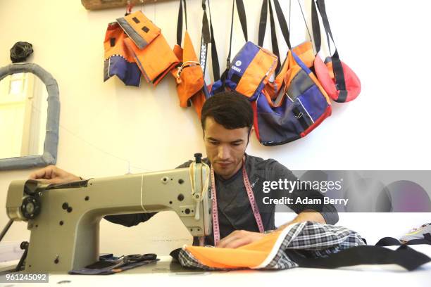 Afghan refugee Amir Mohammadi sews life preserver material and fabric together to make a bag at the Lesvos Solidarity organization's Safe Passage...