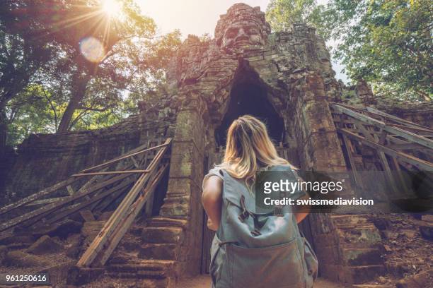 turista che viaggia donne si trova di fronte al cancello complesso del tempio guardando la scultura in cima, concetto di esplorazione della scoperta delle persone - angkor wat foto e immagini stock