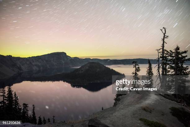 scenic view of crater lake national park against star trails during sunset - wizard island stock pictures, royalty-free photos & images