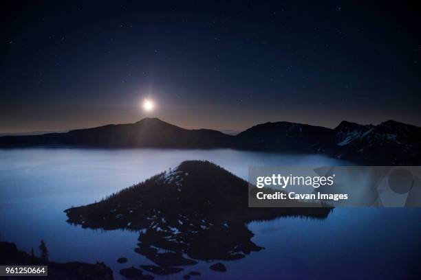 idyllic view of wizard island amidst crater lake against sky during sunrise - wizard island stock pictures, royalty-free photos & images