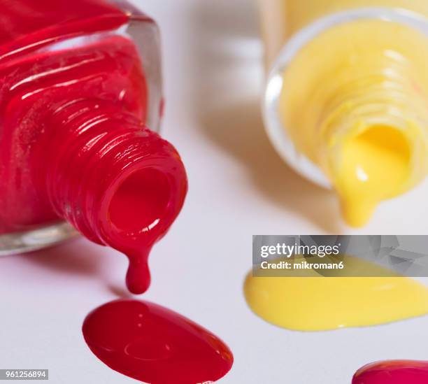 red and yellow nail varnish spilling onto white background. - mikroman6 imagens e fotografias de stock