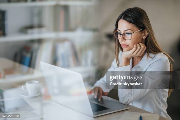 junge schöne geschäftsfrau, die auf ihrem computer im büro arbeiten. - economist stock-fotos und bilder