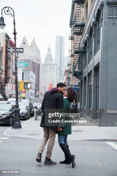 full length of business couple kissing while standing on city street - businesswoman nyc stockfoto's en -beelden