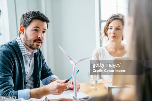 business people discussing about wind turbine model in office - structure actionnée par le vent photos et images de collection