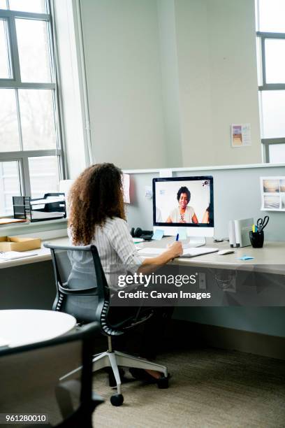 rear view of businesswoman video conferencing with female colleague over desktop computer in office - conference call imagens e fotografias de stock