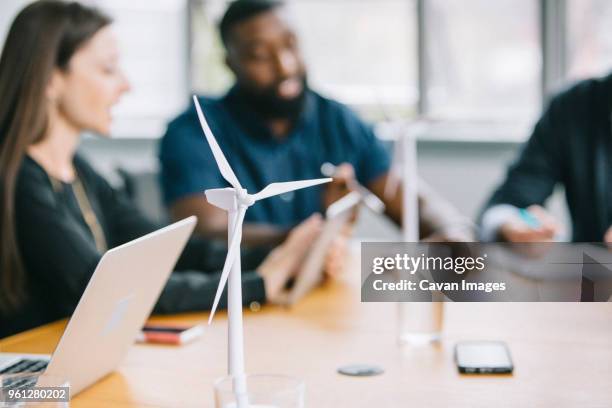 business people discussing over wind turbine models during meeting - new business model stock pictures, royalty-free photos & images