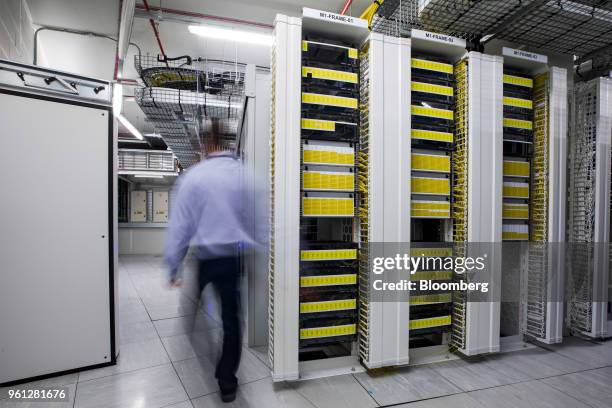 An employee walks past racks of panels inside a communications room at an office in London, U.K., on Monday, May 21, 2018. The Department of Culture,...