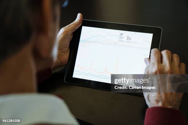 cropped image of senior man studying graph on tablet computer in financial advisors office - tablet hands stock pictures, royalty-free photos & images