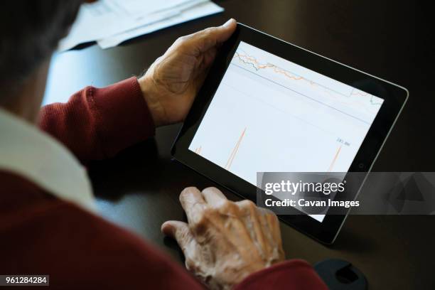 cropped image of senior man examining graph on tablet computer in financial advisors office - assessment graph stock-fotos und bilder