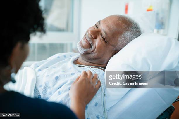 cropped image of daughter touching father lying on bed in hospital ward - salman bildbanksfoton och bilder