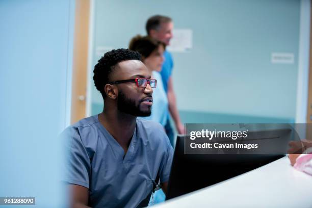 doctor working at hospital reception with colleagues in background - reception 2017 ストックフォトと画像