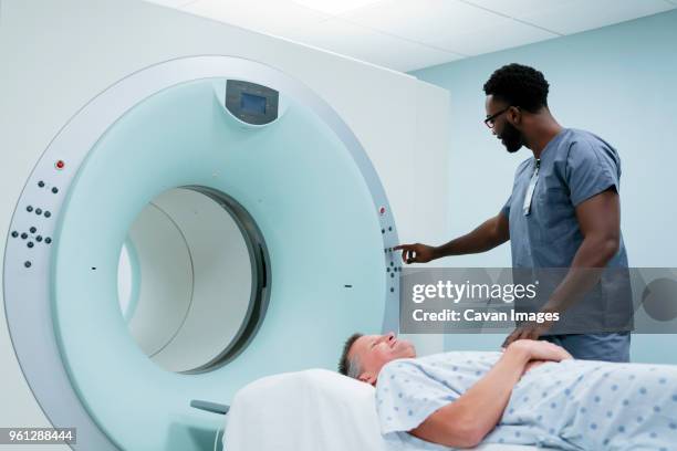 male nurse adjusting button on mri scanner while patient lying in examination room - press screening stock pictures, royalty-free photos & images