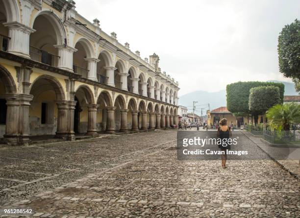 rear view of woman standing on street by captain general palace - antigua guatemala stock pictures, royalty-free photos & images
