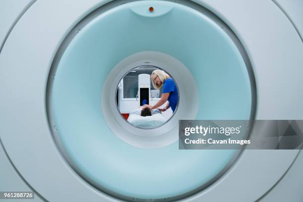 nurse preparing patient for mri scan in hospital seen through scanner - mri technician stock pictures, royalty-free photos & images