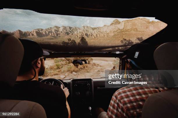 rear view of friends traveling in off-road vehicle on dirt road - two cars ストックフォトと画像