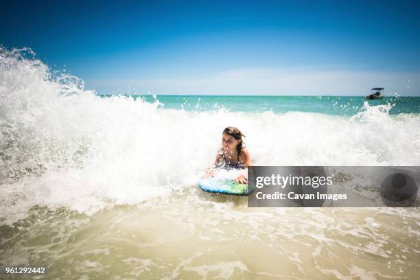 girl surfing in sea against clear sky - anna maria island foto e immagini stock