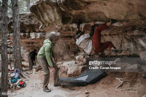 man looking at friend climbing rock at red rock canyon national conservation area - nevada hiking stock pictures, royalty-free photos & images