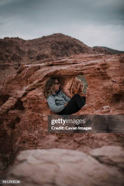 hiker relaxing in rock formation against sky at red rock canyon national conservation area - red rock formation stock pictures, royalty-free photos & images