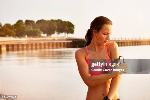 female athlete adjusting arm band at beach - chicago band stock pictures, royalty-free photos & images