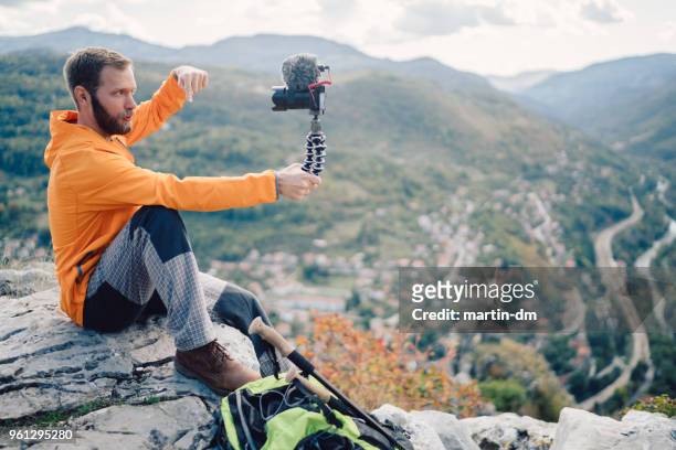 influencer tourist hiking and vlogging on the mountain top - the weekend in news around the world imagens e fotografias de stock